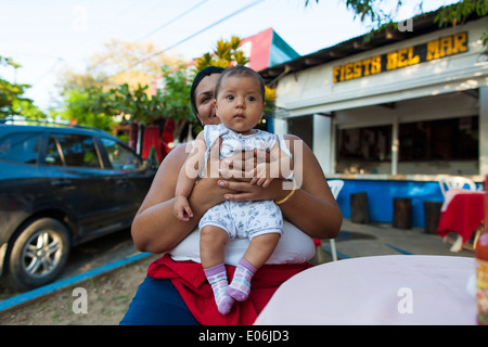 Une femme du Costa Rica est titulaire d'une fille de bébé dans ses mains à Tamarindo Costa Rica. Les enfants sont au cœur de la culture sociale du Costa Rica Banque D'Images