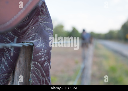 Bottes sur une clôture en fil barbelé Banque D'Images