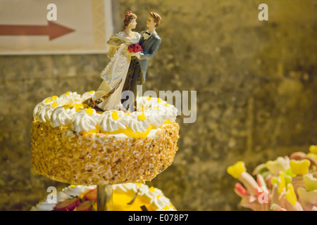 Un époux et dolls sur un gâteau de mariage sur le point de tomber Banque D'Images