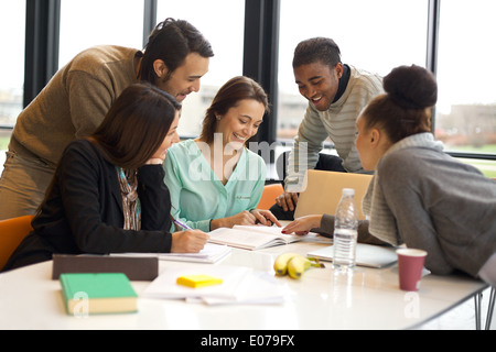 Groupe de professionnels jeunes étudiants en coopération avec leur travail scolaire. Les jeunes multiethniques sitting at table lecture. Banque D'Images