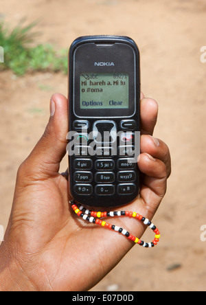 Bushman montrant un message texte en langue San sur son téléphone portable, la Namibie, Tsumkwe Banque D'Images