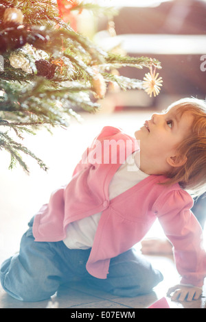 Petite fille en vertu de l'arbre de Noël à la surprise Banque D'Images