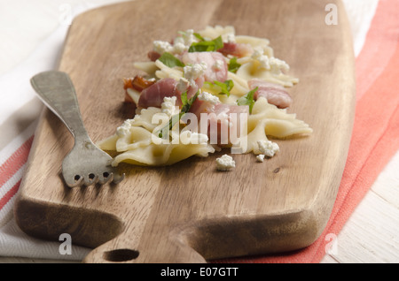 Farfalle et nouilles à la pancetta et au fromage cottage sur une planche en bois Banque D'Images