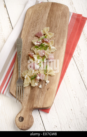 Farfalle et nouilles à la pancetta et au fromage cottage sur une planche en bois Banque D'Images