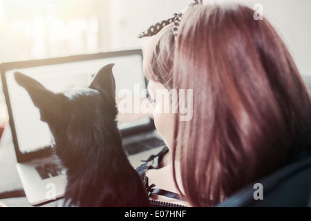 Jeune femme avec son chien looking at laptop Banque D'Images