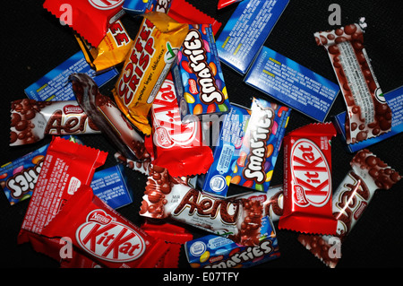 Une pile d'Aero, Coffee Crisp, Kit Kat chocolat Smarties et photographié sur un fond noir. Banque D'Images