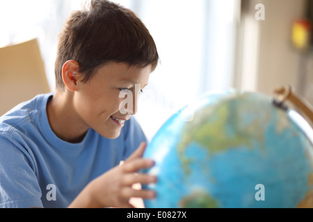 Y0Young boy rêve de parcourir comme il regarde un globe Banque D'Images