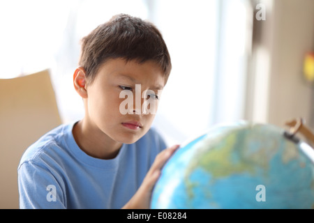 Y0Young boy rêve de parcourir comme il regarde un globe Banque D'Images