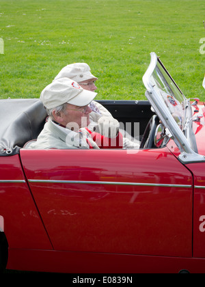 Un homme conduisant un rouge 1962 MG Midget Mk1 avec une passagère Banque D'Images