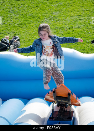 Une jeune fille monte un simulateur de surf Banque D'Images