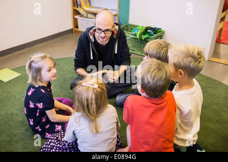 Le professeur et les élèves assis sur un tapis à la maternelle Banque D'Images