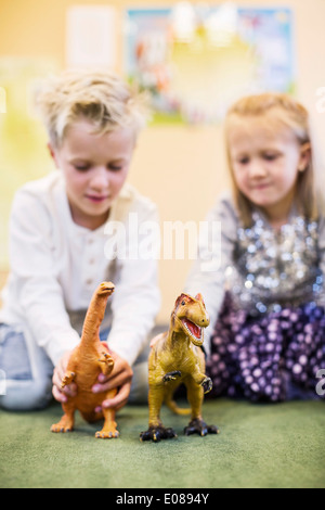 Enfants jouant avec des Dinosaures jouets en maternelle Banque D'Images