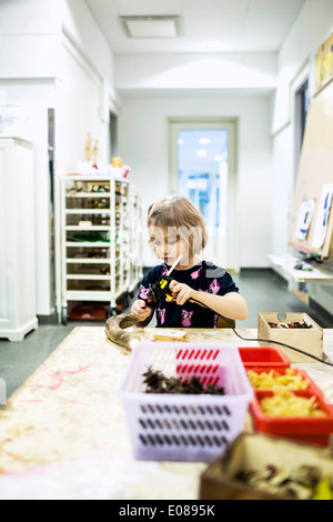 Pistolet à colle à l'aide de jeune fille tablet en maternelle la classe d'art Banque D'Images