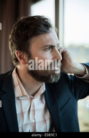 Thoughtful businessman leaning on fenêtre dans hotel Banque D'Images