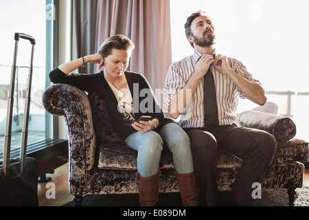 Business couple de détente sur une chaise longue dans la chambre d'hôtel Banque D'Images