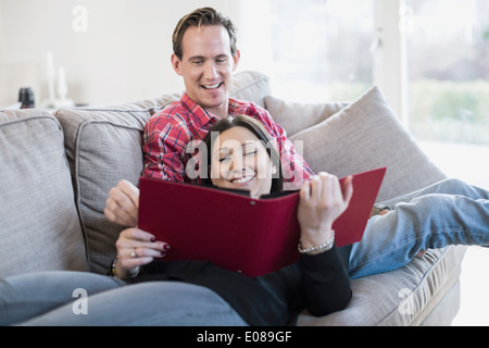 Happy couple looking at photo album ensemble sur canapé Banque D'Images