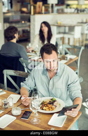 Mid adult businessman using digital tablet tout en déjeunant au restaurant Banque D'Images