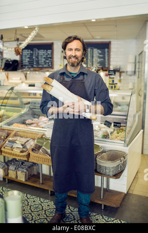 Portrait of mature male baker holding miches de pain en supermarché Banque D'Images