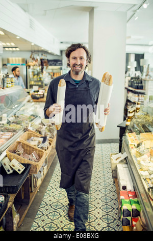 Portrait of mature male baker avec des baguettes de pain en marche supermarché Banque D'Images