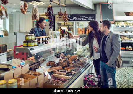 Salesman attending couple at afficher compteur in supermarket Banque D'Images