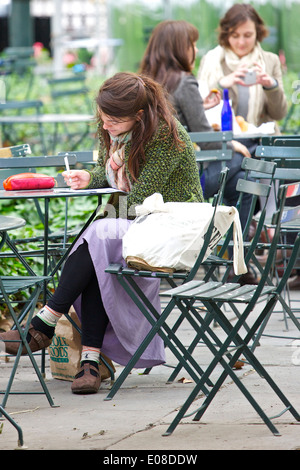 Jeune femme écrit à une table de Bryant Park New York City. Banque D'Images