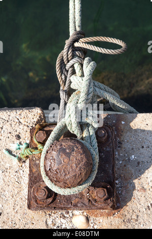 Vieux fer rouillé bollard avec corde liée Banque D'Images