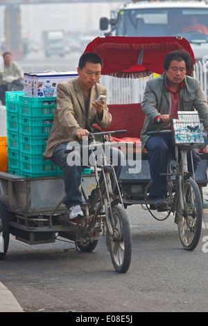 Deux auto rickshaw Drivers dans le pollué l'heure de pointe du matin, Beijing, Chine. Banque D'Images