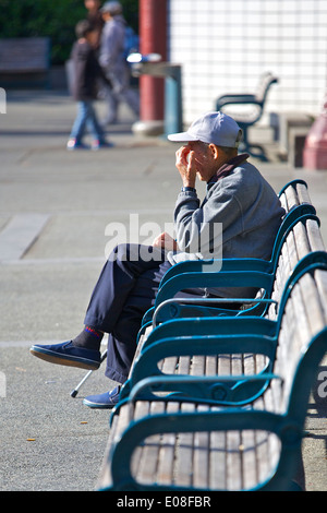 Le repos dans le Square, personnes âgées américain chinois homme assis sur un banc de parc à Portsmouth Square San Francisco. Banque D'Images