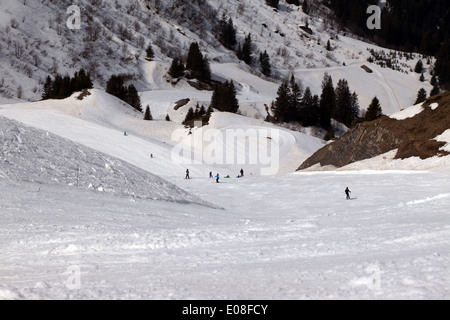 Vue grand angle de skieurs en ordre décroissant Les Arbis piste rouge, dans la station de ski de Morzine, France. Banque D'Images