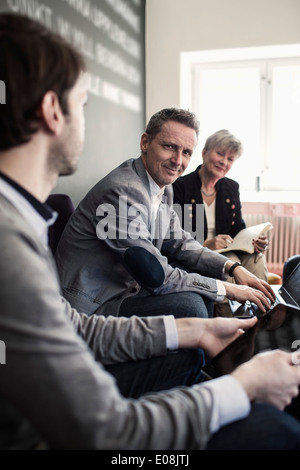 Portrait of smiling businessman avec des collègues in office lobby Banque D'Images