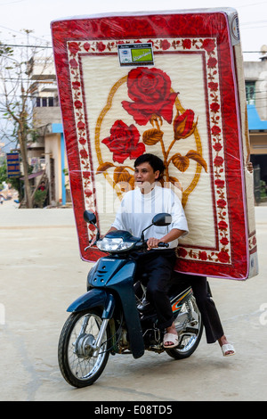 Transport de l'homme vietnamiens un matelas sur sa moto, Bac Ha, province de Lao Cai, Vietnam Banque D'Images