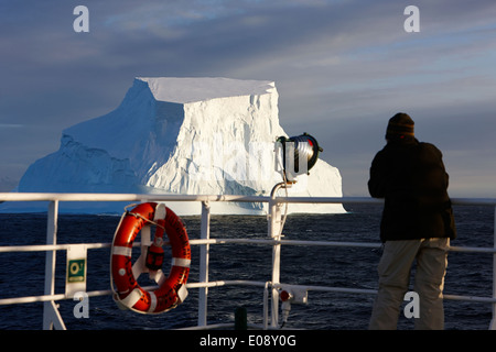 Man taking photograph of iceberg géant à bord d'un navire en antarctique Banque D'Images