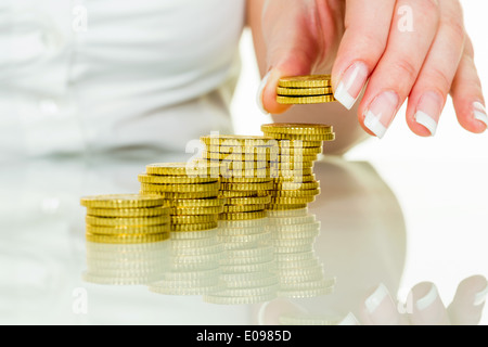 Les piles de pièces d'une femme. De l'argent à épargner pour l'avenir., Eine Frau stapelt Muenzen. Geld sparen fuer die Zukunft. Banque D'Images