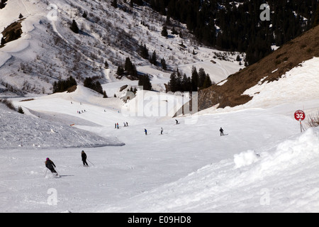Vue grand angle de skieurs en ordre décroissant Les Arbis piste rouge, dans la station de ski de Morzine, France. Banque D'Images
