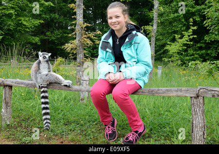 Un teenage girl est assis à côté de l'Untitled document sur la clôture en bois au parc animalier. Banque D'Images