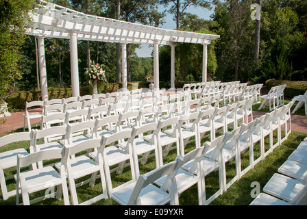 Location blanc chaises sont placées en rangées derrière une pergola en attente d'un mariage d'été en plein air Banque D'Images