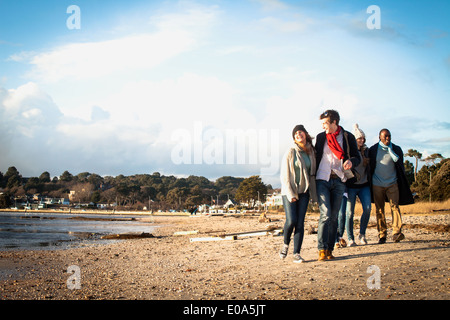 Cinq amis adultes hors marche sur la plage Banque D'Images