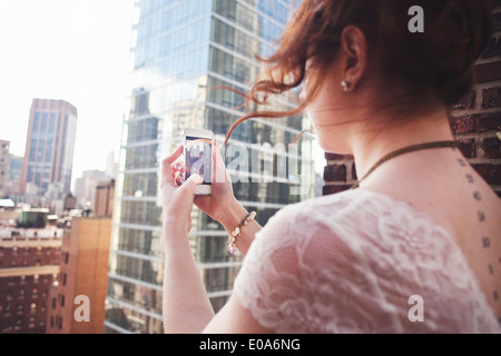 Young woman using smartphone pour photographier Manhattan, New York City Banque D'Images