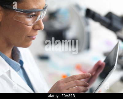 Female scientist viewing résultats d'essai d'un digital tablet in lab Banque D'Images