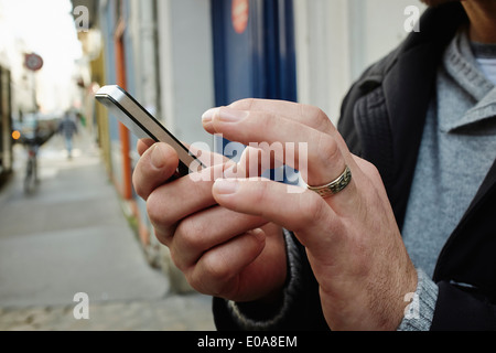 Mid adult man sur trottoir à l'aide d'écran tactile sur smartphone Banque D'Images