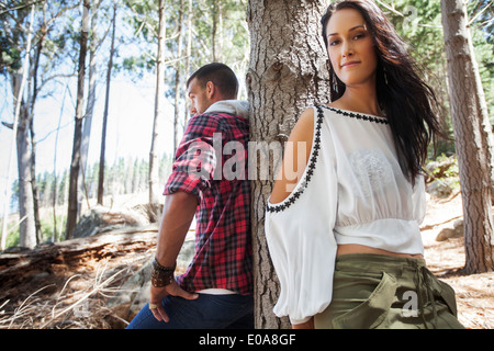 Jeune couple leaning against tree in forest Banque D'Images