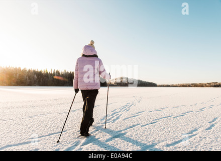 Femme de la marche nordique dans la neige champ couvert Banque D'Images