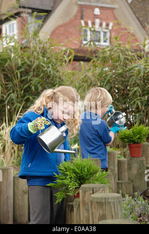 School boy and girl watering plants in garden Banque D'Images
