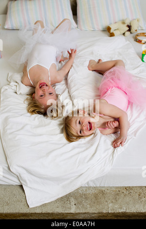 Portrait de deux jeunes sœurs jouer on bed Banque D'Images