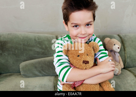 Portrait de jeune garçon sur canapé hugging teddy Banque D'Images