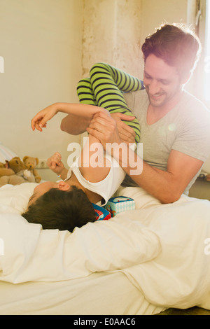 Le père et le jeune fils jouer combats on bed Banque D'Images