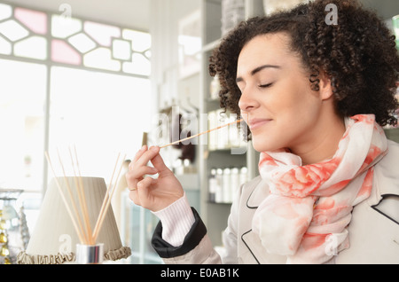 Young woman smelling joss sticks in boutique Banque D'Images