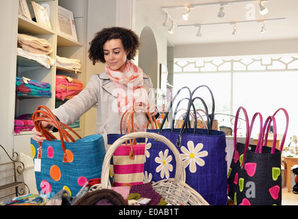 Jeune femme parcourt les sacs en boutique Banque D'Images