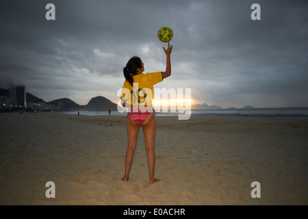 Young woman balancing ballon de soccer sur le doigt, la plage de Copacabana, Rio de Janeiro, Brésil Banque D'Images