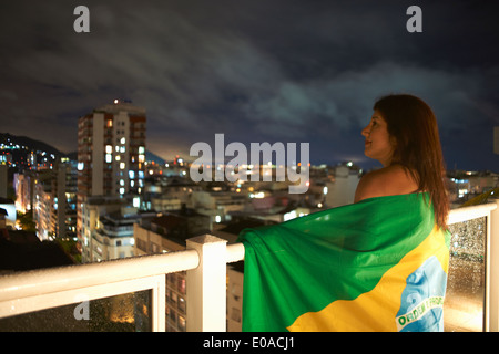 Young woman gazing du balcon la nuit, Rio de Janeiro, Brésil Banque D'Images